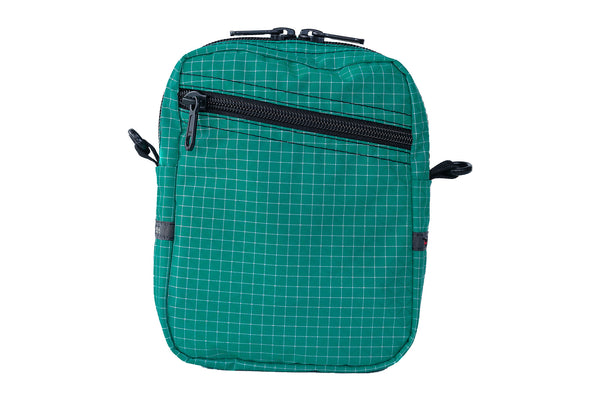 An Everyday Cubelet in Kelpie Halcyon (bluish-green with a white grid) with a front zipper.